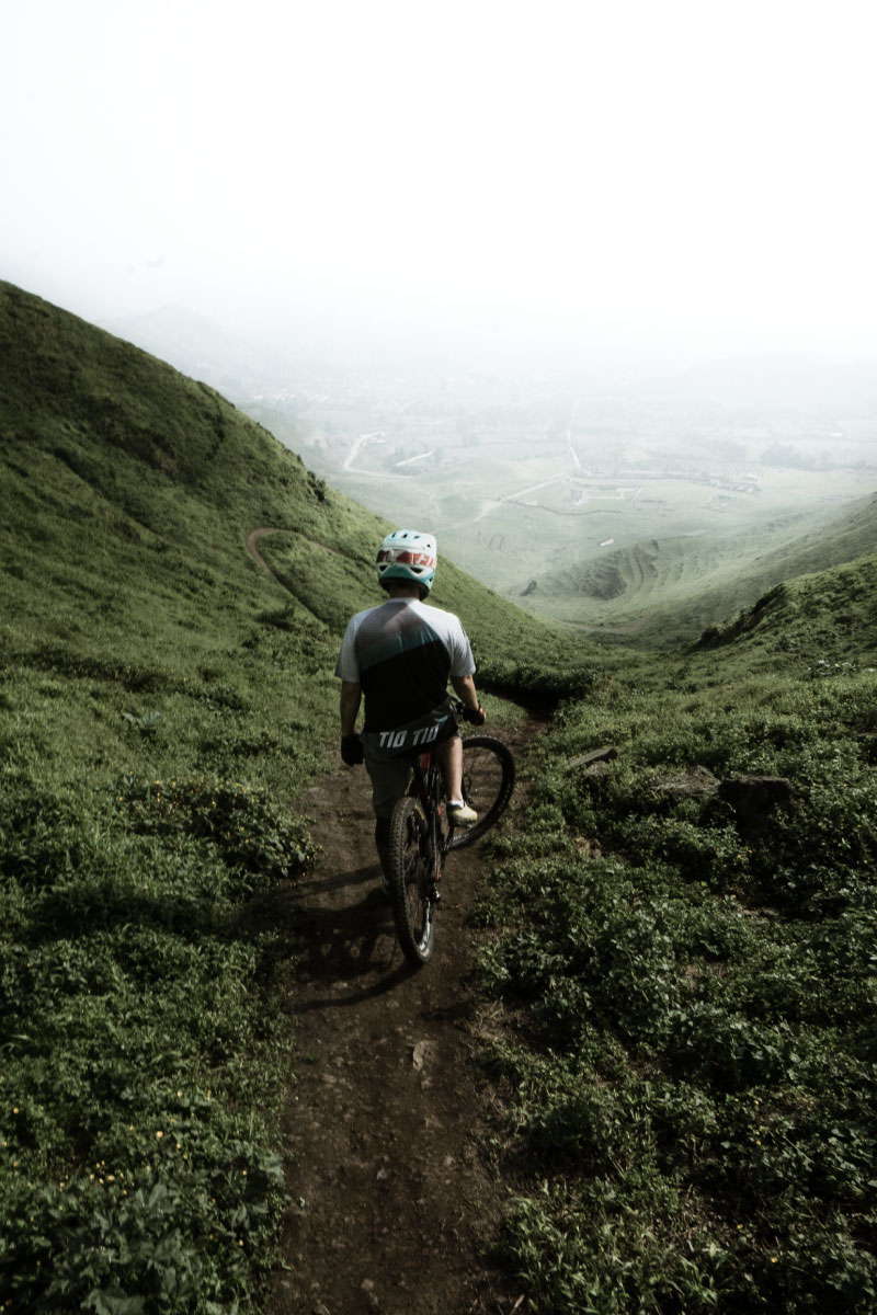 Man with bike looking down a mountain trail
