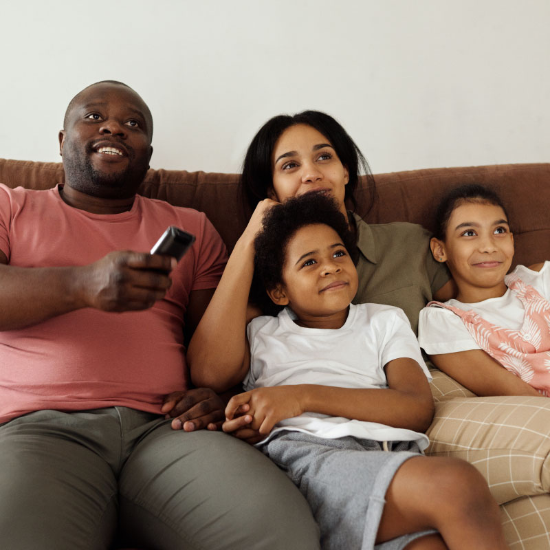 Family of four watching tv on couch