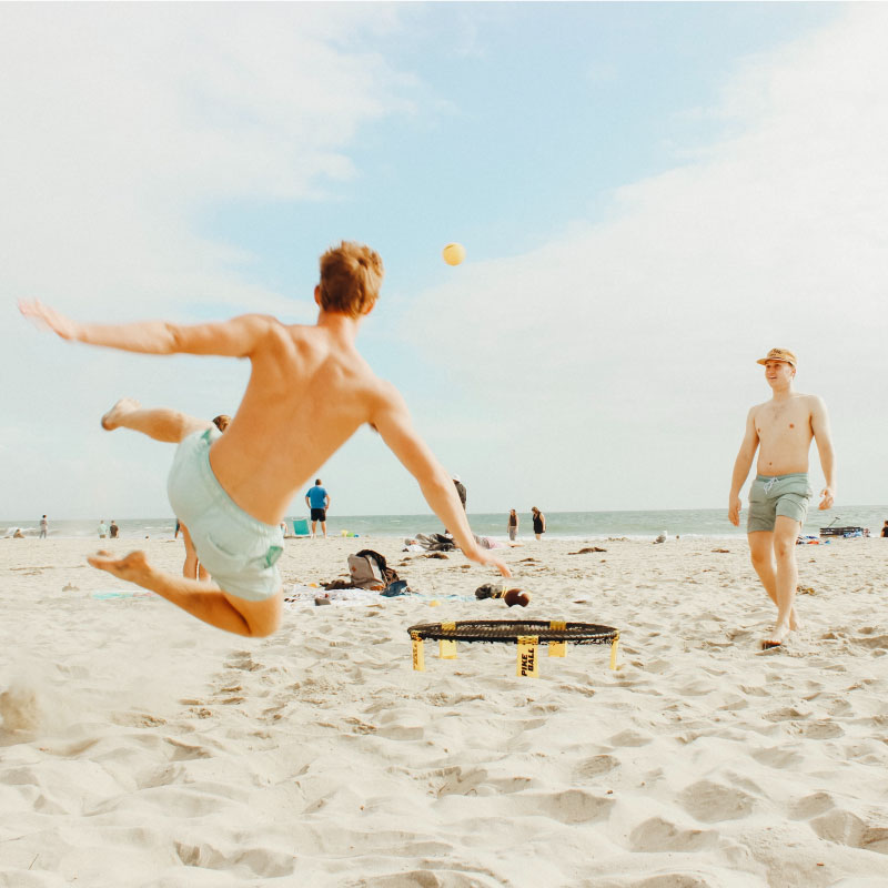 Guys at the beach playing Spikeball