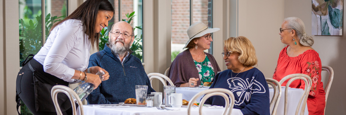 Brookdale employee serving residents lunch at a community dining room.